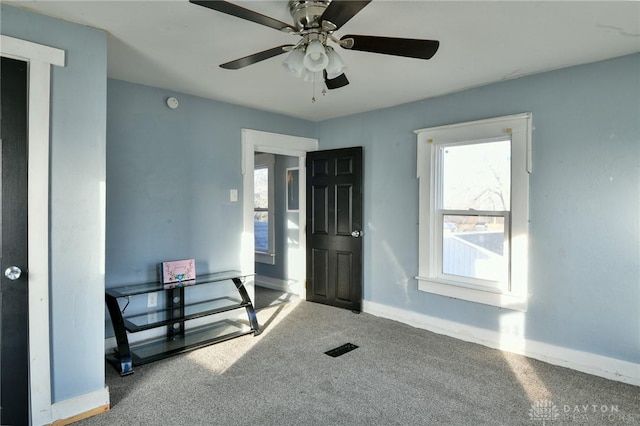 carpeted foyer entrance with a wealth of natural light and ceiling fan