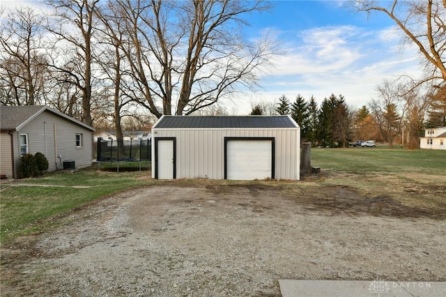 garage featuring a trampoline, a yard, and central air condition unit