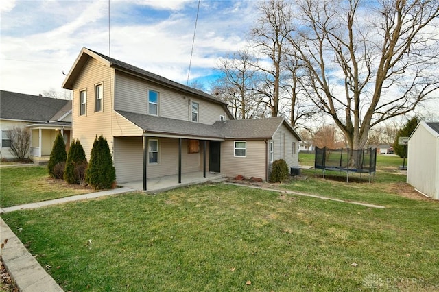 rear view of house with a trampoline, a lawn, and a patio