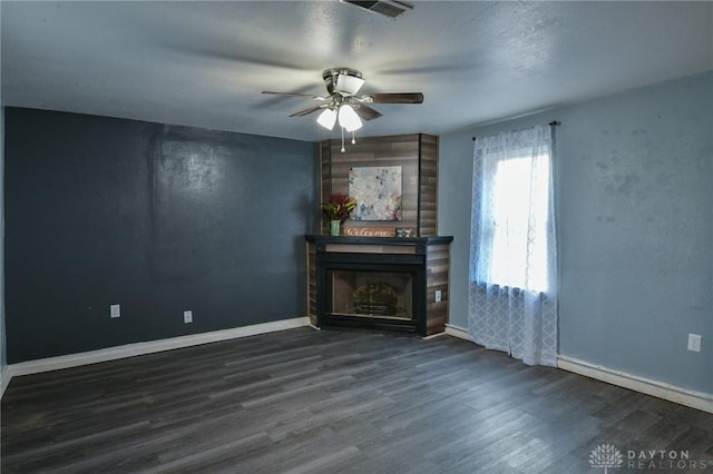 unfurnished living room featuring a large fireplace, dark wood-type flooring, and ceiling fan