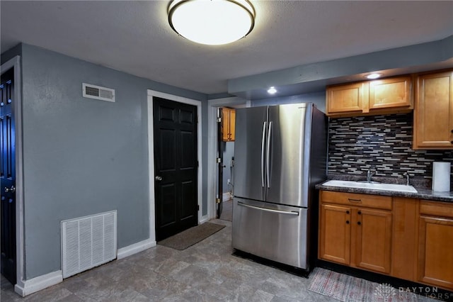 kitchen featuring tasteful backsplash, sink, and stainless steel refrigerator