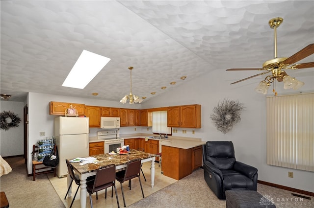 kitchen featuring sink, decorative light fixtures, light colored carpet, lofted ceiling with skylight, and white appliances