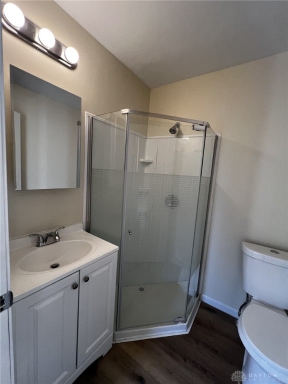 bathroom with vanity, a shower with shower door, wood-type flooring, and toilet