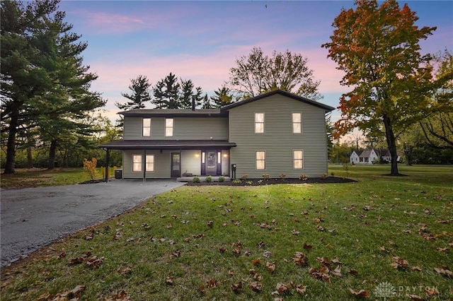 traditional home featuring aphalt driveway and a front yard