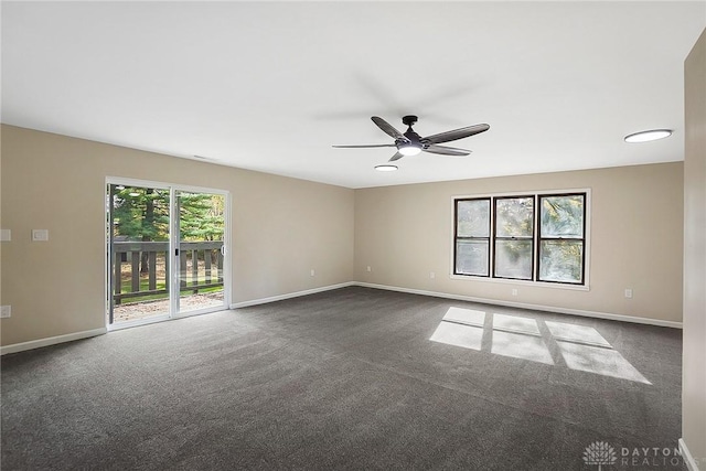 empty room featuring ceiling fan, dark colored carpet, and baseboards