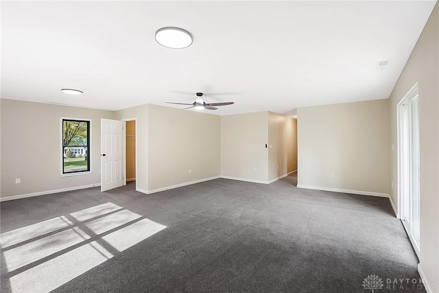 spare room with baseboards, dark colored carpet, and a ceiling fan