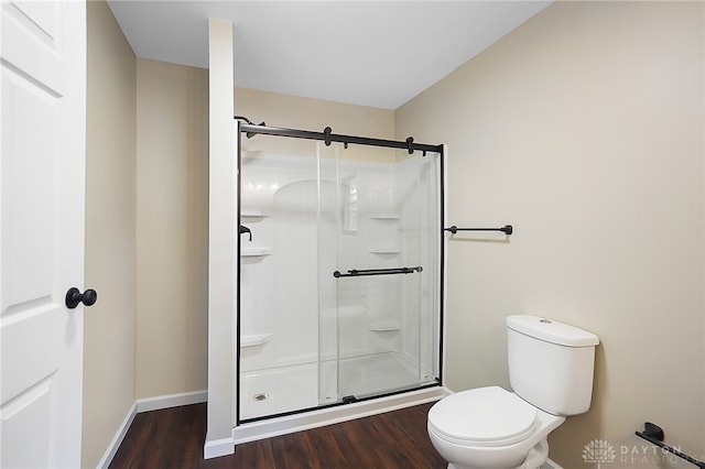 bathroom featuring toilet, an enclosed shower, and wood-type flooring