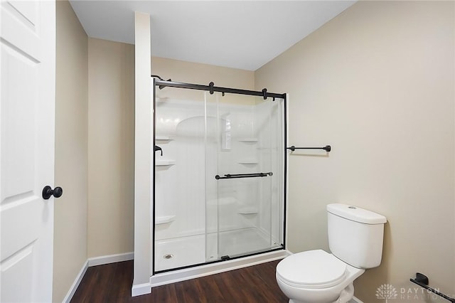 full bathroom with baseboards, wood finished floors, toilet, and a shower stall