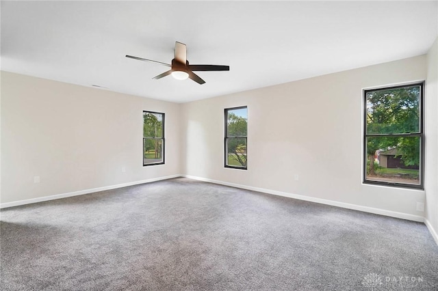 carpeted empty room featuring ceiling fan and baseboards