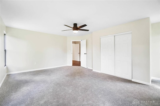 unfurnished bedroom featuring a ceiling fan, baseboards, dark carpet, and a closet