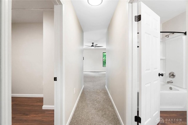 hall with dark colored carpet and baseboards