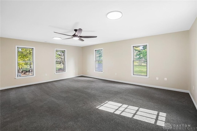 empty room featuring ceiling fan, baseboards, and dark colored carpet