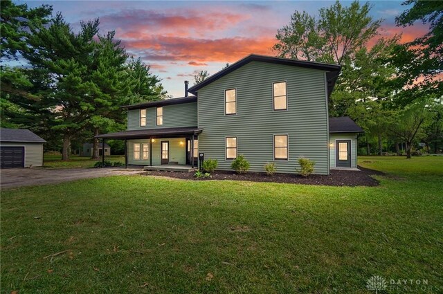 view of front of home featuring covered porch, an outdoor structure, and a lawn