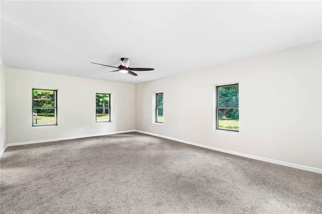 spare room featuring a healthy amount of sunlight, carpet, baseboards, and a ceiling fan