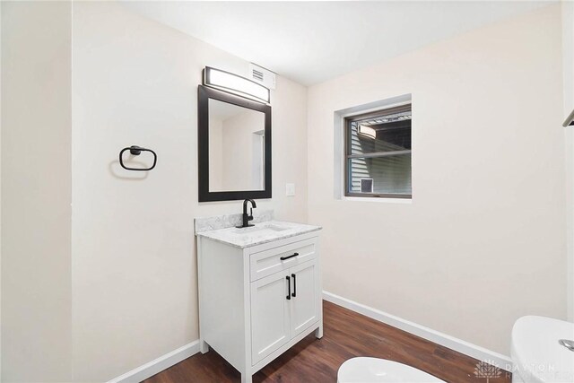 bathroom with toilet, hardwood / wood-style floors, and vanity