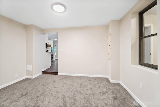 empty room featuring carpet floors and baseboards