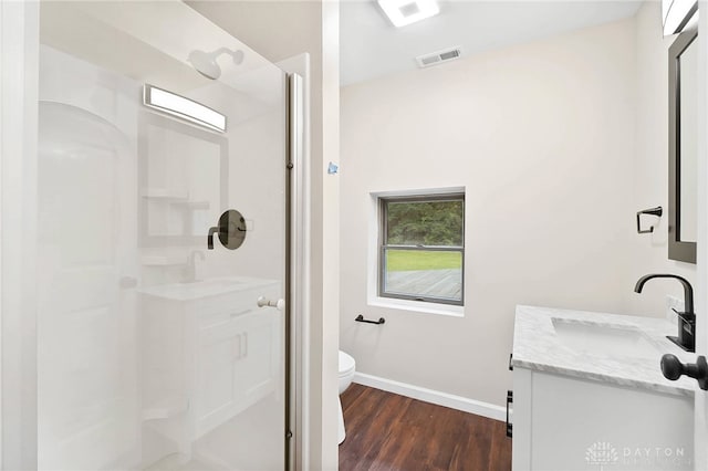 bathroom featuring vanity, hardwood / wood-style flooring, toilet, and walk in shower