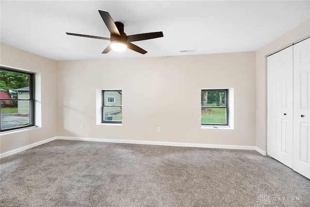 unfurnished bedroom with carpet flooring, multiple windows, a closet, and ceiling fan