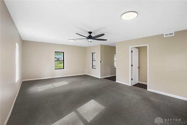 unfurnished room featuring a ceiling fan, dark colored carpet, visible vents, and baseboards