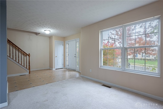 carpeted foyer featuring a textured ceiling