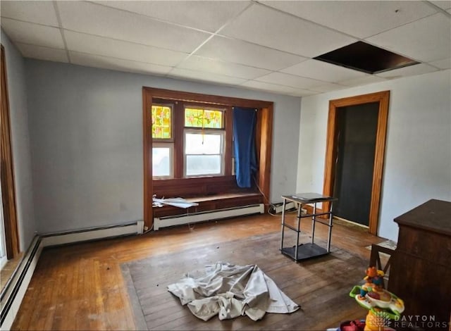 interior space featuring a paneled ceiling, dark wood-type flooring, and a baseboard radiator