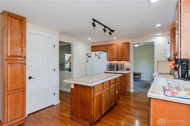 kitchen with backsplash, a kitchen island, light wood-type flooring, and white appliances