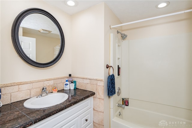 bathroom with vanity, shower / washtub combination, and tile walls