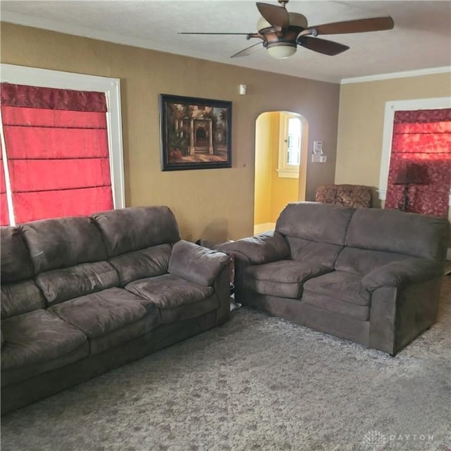 carpeted living room with crown molding and ceiling fan