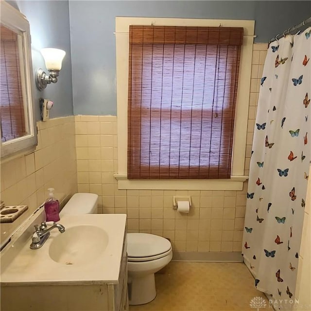 bathroom with a shower with curtain, vanity, tile walls, and toilet