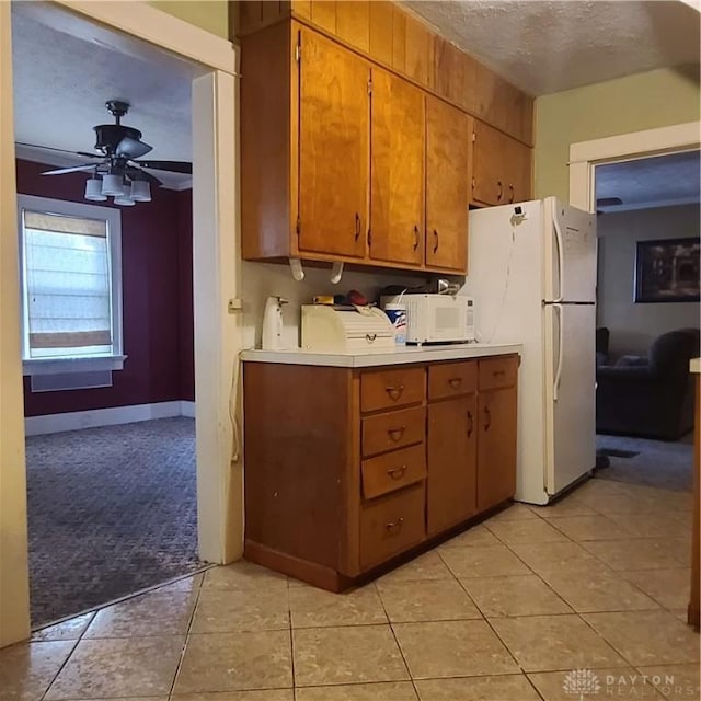 kitchen with a textured ceiling, ceiling fan, light tile patterned flooring, and white appliances