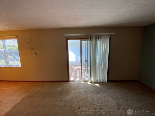 carpeted spare room with a textured ceiling