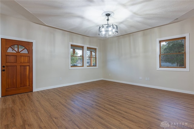 entryway featuring dark wood-type flooring, a chandelier, and a textured ceiling