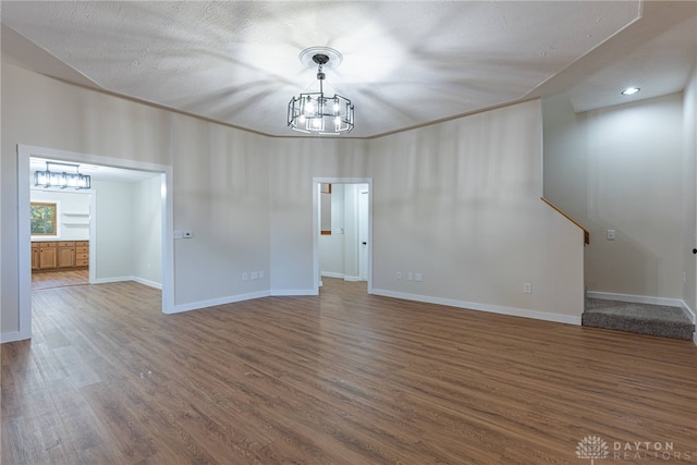 spare room featuring dark wood-type flooring, an inviting chandelier, and a textured ceiling