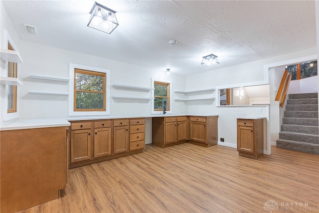 kitchen with a textured ceiling, light wood-type flooring, and sink