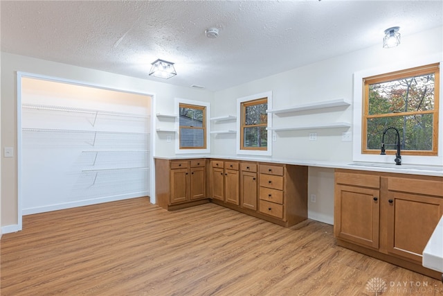 kitchen with sink, a textured ceiling, and light wood-type flooring