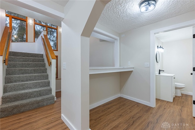 stairs with sink, hardwood / wood-style floors, and a textured ceiling