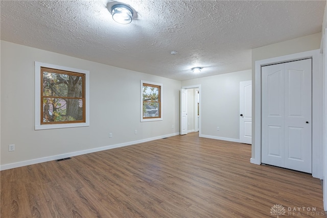 unfurnished room with a textured ceiling and hardwood / wood-style floors