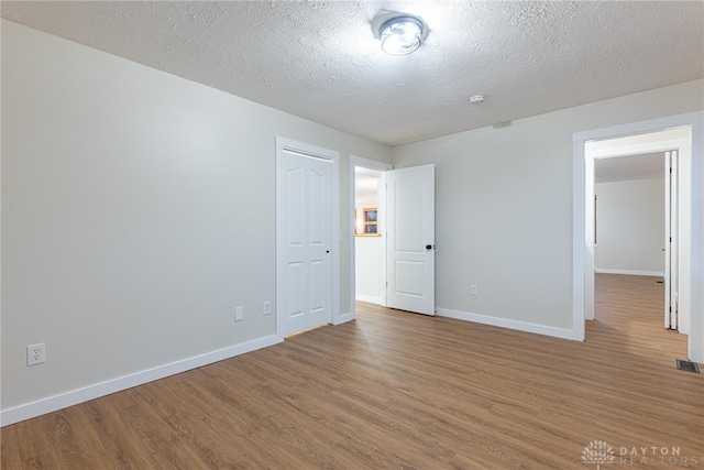 unfurnished room with hardwood / wood-style flooring and a textured ceiling