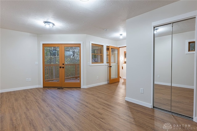 empty room with french doors, a textured ceiling, and wood-type flooring