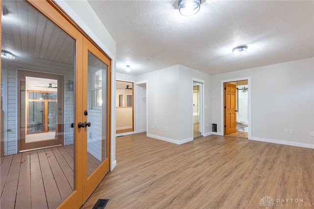 spare room with a textured ceiling, wood-type flooring, and french doors