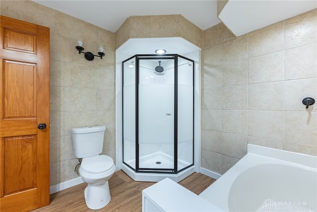 bathroom featuring toilet, independent shower and bath, tile walls, and wood-type flooring