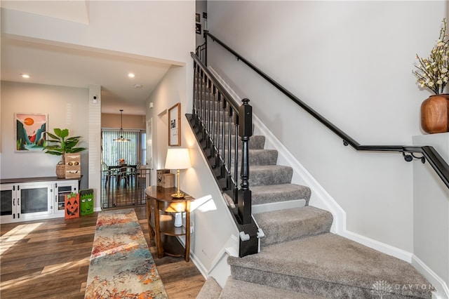 staircase with hardwood / wood-style flooring and an inviting chandelier