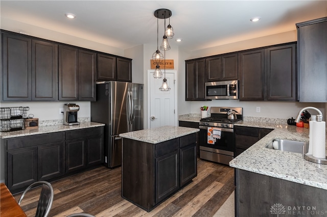 kitchen with a kitchen island, appliances with stainless steel finishes, dark wood-type flooring, pendant lighting, and sink