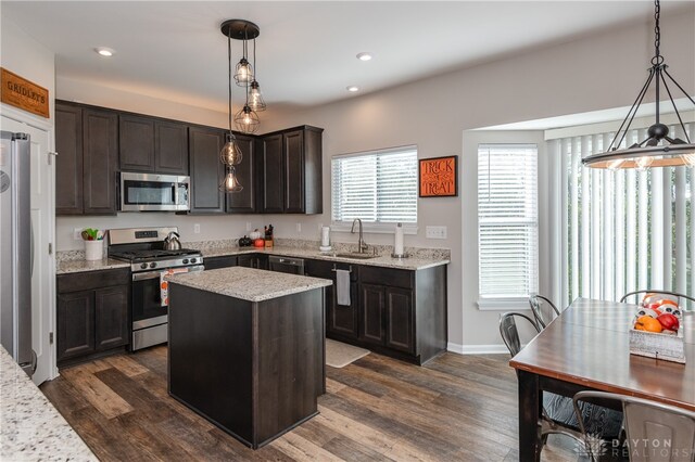 kitchen featuring appliances with stainless steel finishes, sink, a center island, dark hardwood / wood-style flooring, and pendant lighting