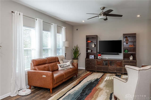 living room with dark wood-type flooring, ceiling fan, and a wealth of natural light