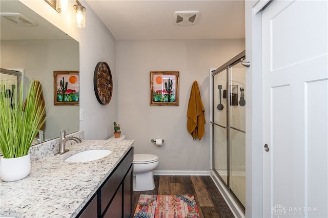 bathroom with a shower with door, vanity, wood-type flooring, and toilet