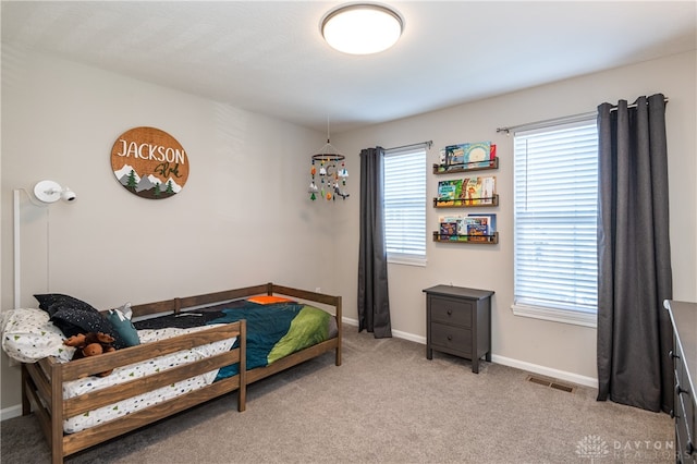 bedroom with multiple windows and light colored carpet