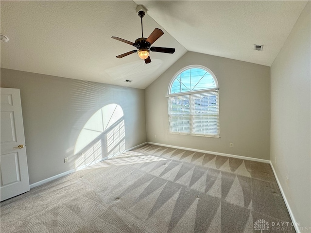 carpeted spare room featuring ceiling fan, a textured ceiling, and vaulted ceiling