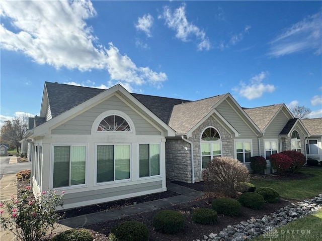 view of home's exterior featuring stone siding and a shingled roof