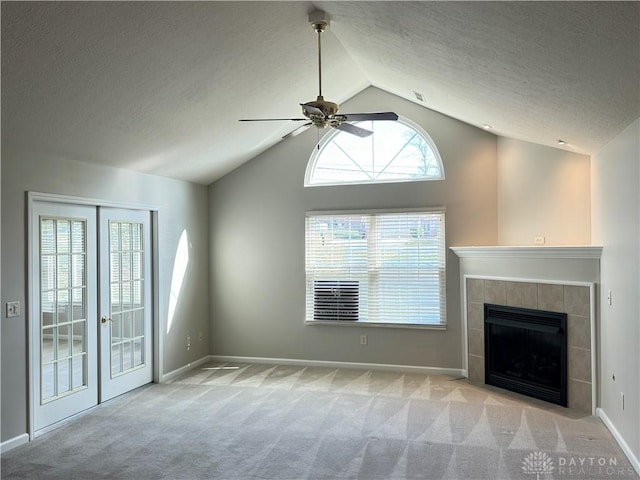 unfurnished living room featuring a tile fireplace, a ceiling fan, lofted ceiling, and carpet